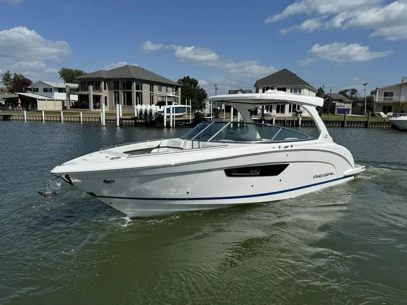 Slide: The Image of 2025 Regal 3300 boat cruising on a sunny day in a residential canal. - 3