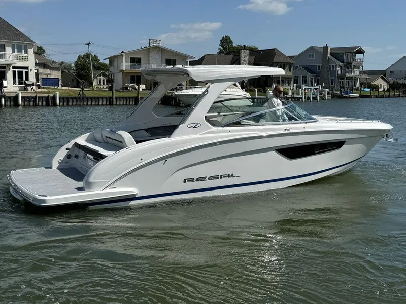 Slide: The Image of 2025 Regal 3300 boat cruising on a sunny waterfront near houses. - 5