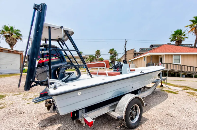 Slide: The Image of 1996 Hewes Tunnel boat on a trailer, parked outdoors near buildings and palm trees. - 7