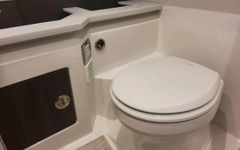 Slide: The Image of 2025 Formula 330 Crossover Bowrider I/O bathroom with modern toilet and storage cabinet. - 17