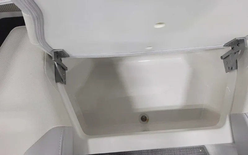Slide: The Image of 2025 Formula 330 Crossover Bowrider I/O storage compartment with open lid and drain plug. - 32