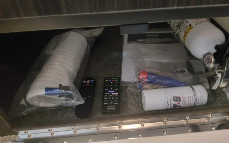 Slide: The Image of Storage compartment in 2025 Formula 330 Crossover Bowrider I/O with remotes, documents, and safety equipment. - 14