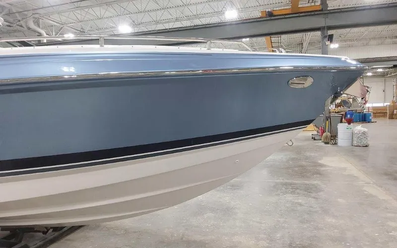 Slide: The Image of 2025 Formula 330 Crossover Bowrider I/O in a showroom, showcasing sleek blue hull design. - 7