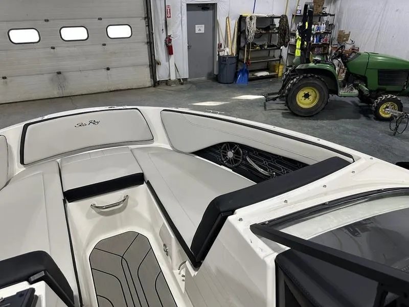 Slide: The Image of 2025 Sea Ray SPX 190 OB boat interior in a garage with tractor nearby. - 6