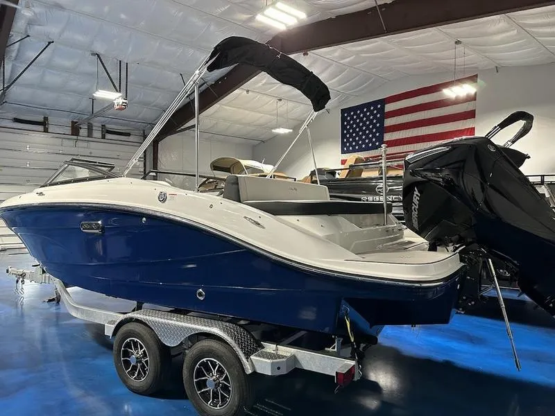 Slide: The Image of 2025 Sea Ray SPX 210 OB boat in showroom with American flag backdrop. - 3