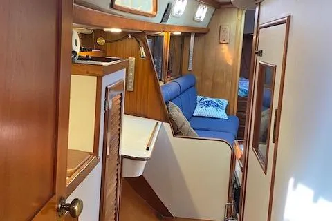 Slide: The Image of Interior of 1989 Morgan 44 Center Cockpit sailboat with wooden finishes and blue seating. - 14