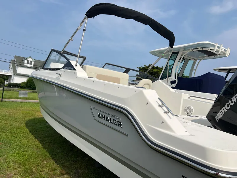 The Image of 2025 Boston Whaler 210 Vantage boat with canopy, displayed on grass. - 0