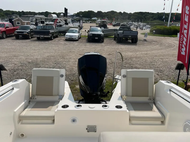 Slide: The Image of 2025 Boston Whaler 210 Vantage boat interior with seating and motor, parked in a marina. - 18