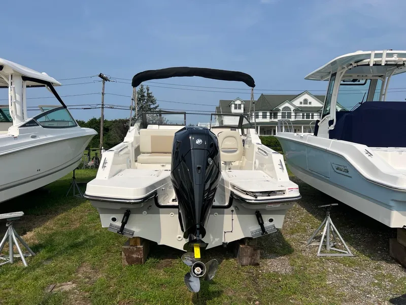 Slide: The Image of 2025 Boston Whaler 210 Vantage boat displayed outdoors, rear view with outboard motor. - 2