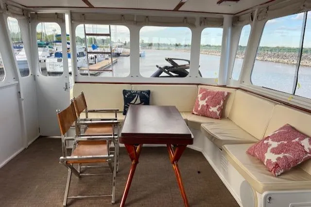 Slide: The Image of 1970 Huckins Offshore yacht interior with seating, table, and marina view. - 10