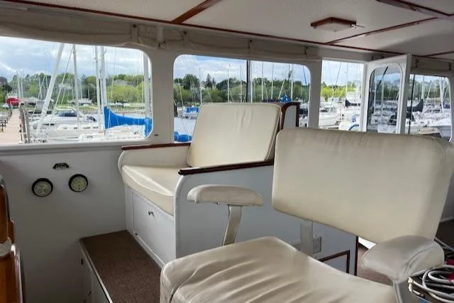 Slide: The Image of Interior of a 1970 Huckins Offshore boat with white seating and marina view. - 15