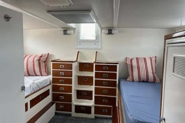 Slide: The Image of 1970 Huckins Offshore boat cabin with twin beds and striped pillows. - 19