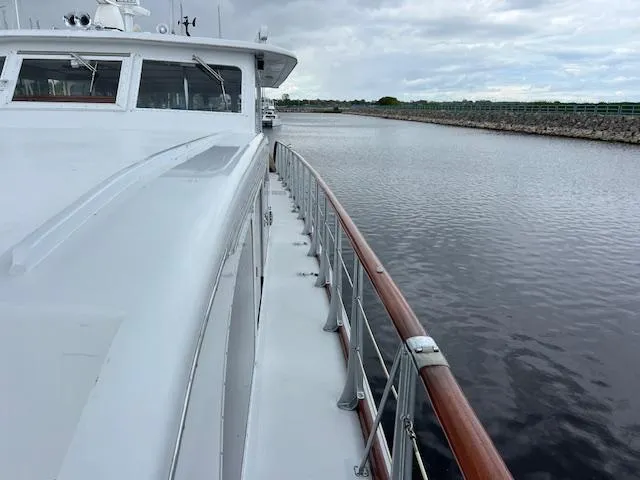 Slide: The Image of 1970 Huckins Offshore yacht on calm water with wooden railings and overcast sky. - 2