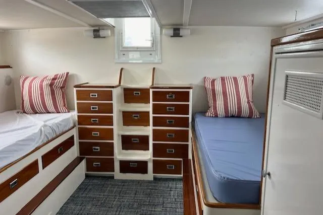 Slide: The Image of 1970 Huckins Offshore boat cabin with twin beds and ample storage. - 21