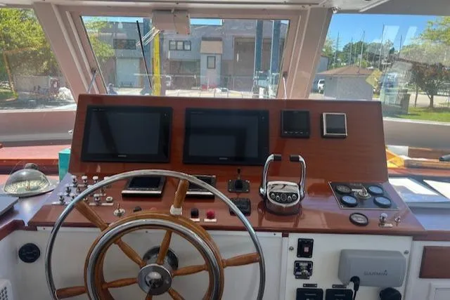 Slide: The Image of 1970 Huckins Offshore boat helm with wooden steering wheel and modern navigation equipment. - 9