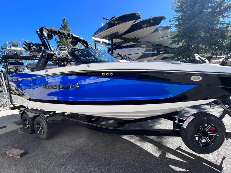 Slide: The Image of 2024 MasterCraft X24 boat in blue and black on a trailer. - 0