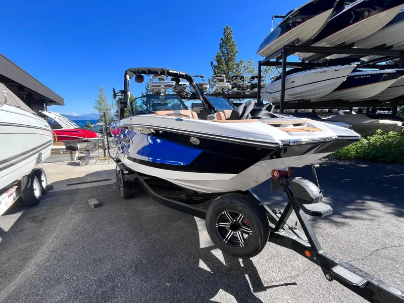 Slide: The Image of 2024 MasterCraft X24 boat on trailer in marina under clear blue sky. - 5