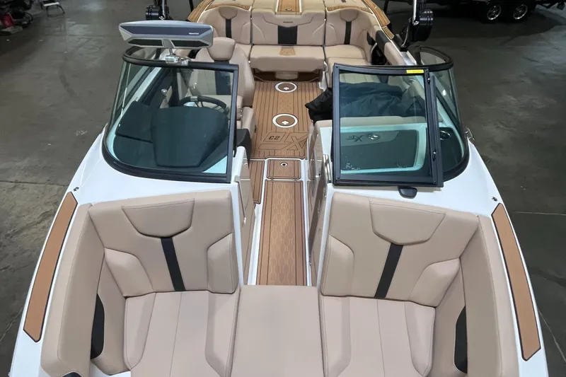 Slide: The Image of 2024 MasterCraft XT23 boat interior with beige seating and wood accents. - 14