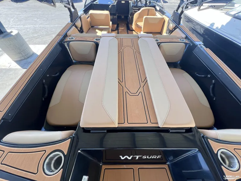 Slide: The Image of 2024 Heyday WT Surf boat interior with tan and beige seating, cup holders, and wood accents. - 3