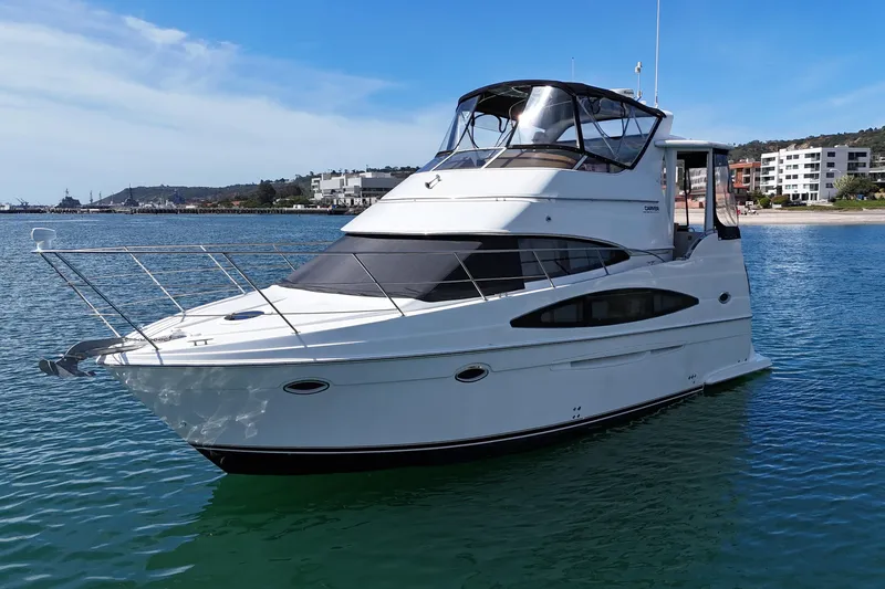 The Image of 2004 Carver 366 Motor Yacht on calm water near a coastal cityscape. - 0