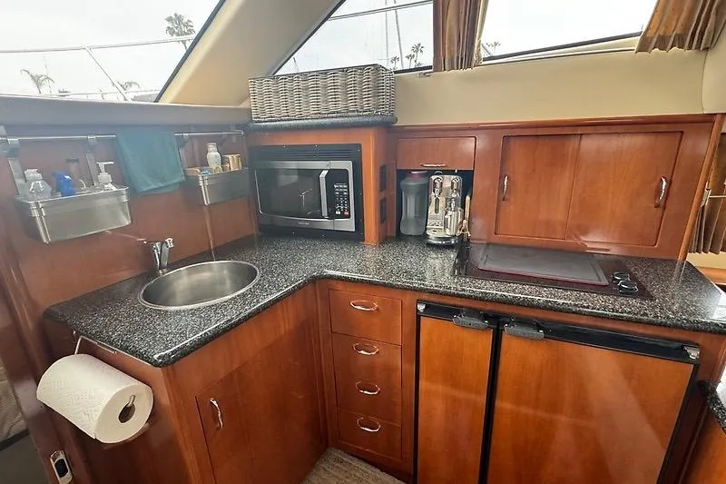 Slide: The Image of 2004 Carver 366 Motor Yacht kitchen with granite countertops, microwave, and wooden cabinetry. - 14