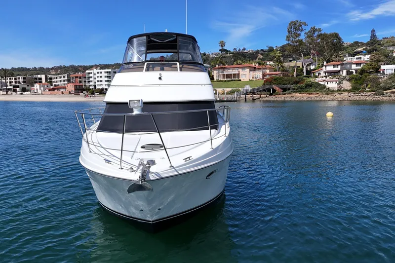 Slide: The Image of 2004 Carver 366 Motor Yacht on calm water near coastal homes. - 2