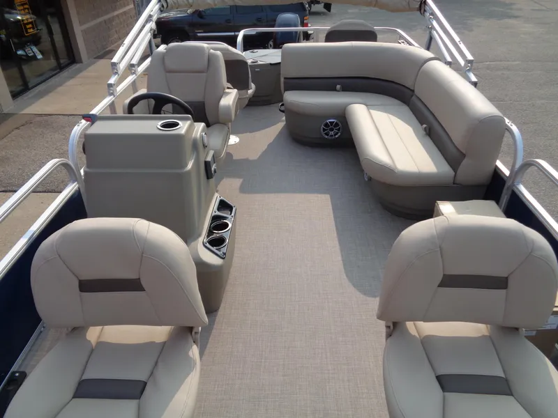 Slide: The Image of 2024 Sun Tracker Bass Buggy 18 DLX pontoon boat interior with beige seating and steering console. - 4