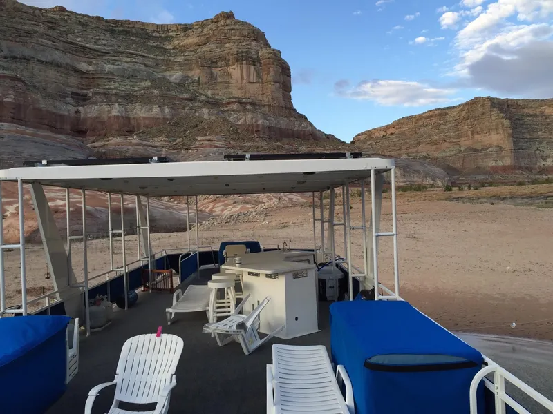 Slide: The Image of 2001 Skipperliner houseboat on a dry, rocky landscape with cliffs in the background. - 2