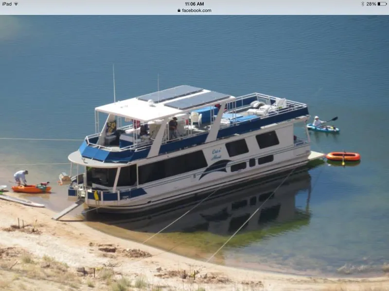 Slide: The Image of 2001 Skipperliner houseboat docked on a calm lake with people kayaking nearby. - 6