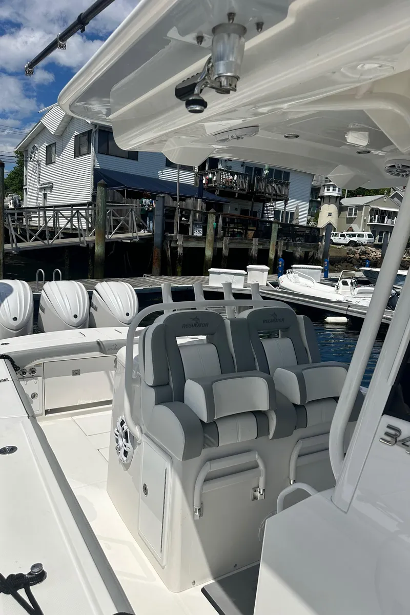 Slide: The Image of 2022 Regulator 34 boat interior with seating, docked near waterfront homes. - 11