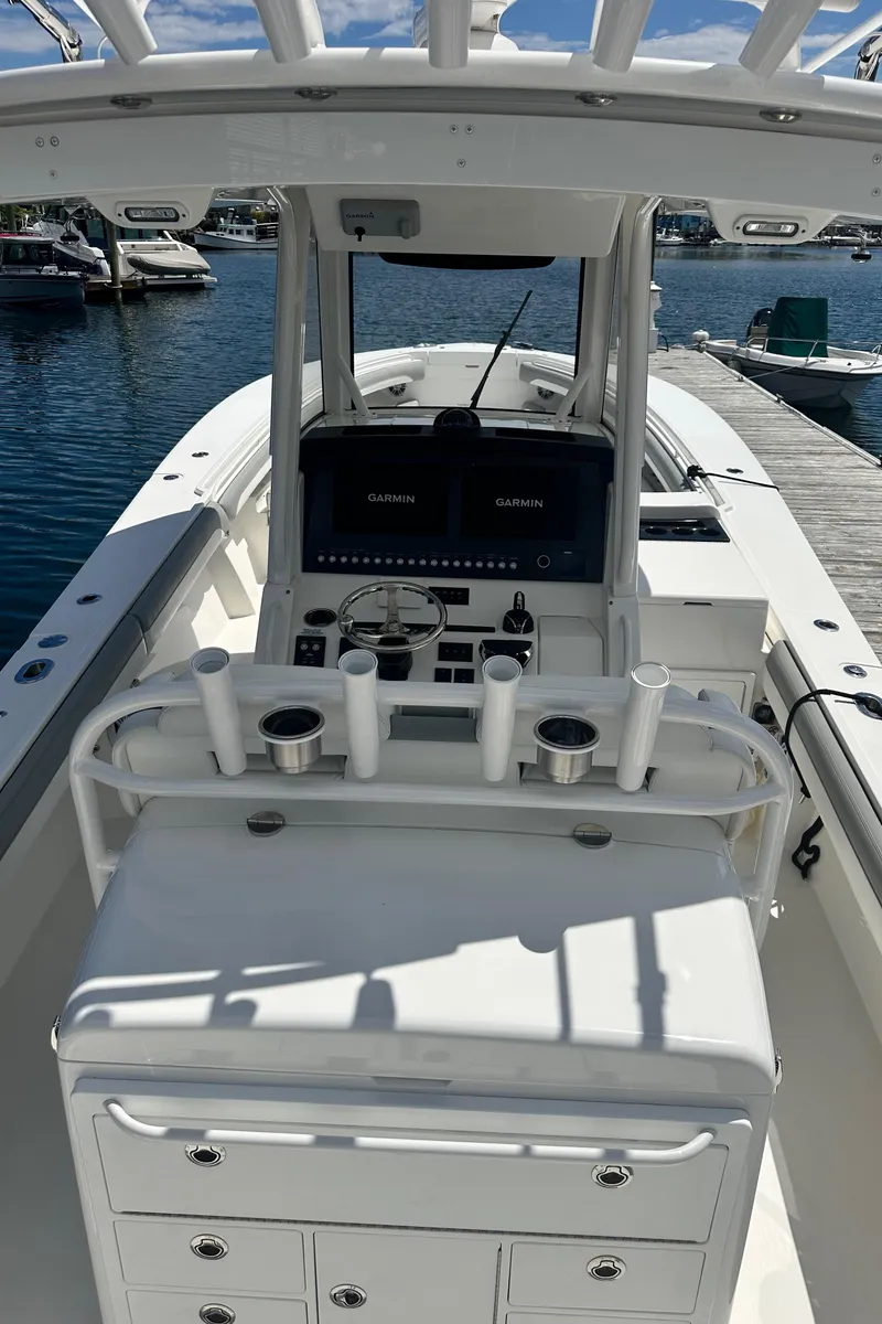 Slide: The Image of 2022 Regulator 34 boat interior with helm, rod holders, and storage, docked by the water. - 4