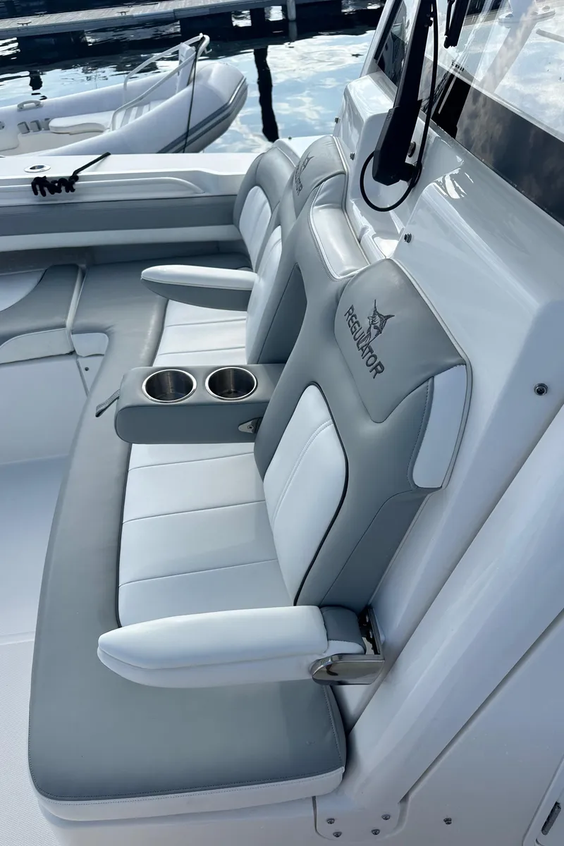 Slide: The Image of 2022 Regulator 34 boat interior with gray and white seating, featuring cup holders. - 24