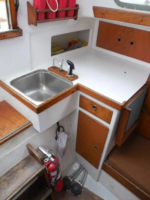 Slide: The Image of 1961 Rhodes Swiftsure boat interior with sink, wooden cabinets, and fire extinguisher. - 10