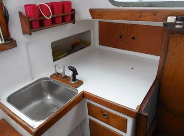 Slide: The Image of 1961 Rhodes Swiftsure boat galley with sink, countertop, and red cup storage. - 11