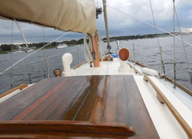 Slide: The Image of 1961 Rhodes Swiftsure sailboat deck with wooden finish on a calm lake. - 16