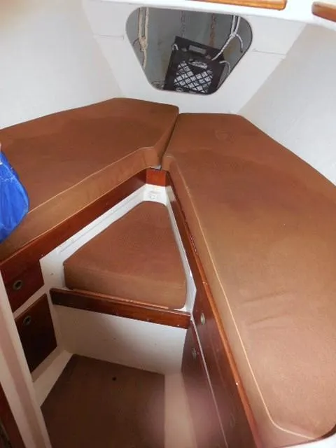 Slide: The Image of 1961 Rhodes Swiftsure cabin interior with brown cushions and wooden accents. - 32