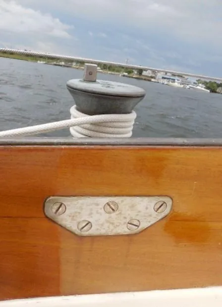 Slide: The Image of 1961 Rhodes Swiftsure sailboat detail with cleat and rope on wooden deck. - 39
