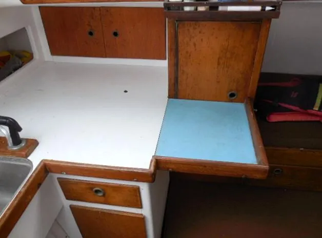 Slide: The Image of 1961 Rhodes Swiftsure boat interior with wooden cabinetry and compact kitchen area. - 9