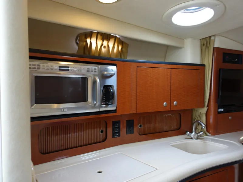 Slide: The Image of 2005 Sea Ray 320 Sundancer kitchen with microwave, sink, and wooden cabinets. - 15