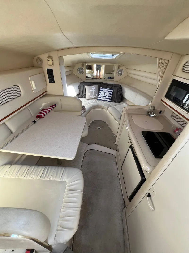 Slide: The Image of Interior of 2001 Sea Ray 270 Sundancer with seating, table, kitchenette, and nautical-themed decor. - 15