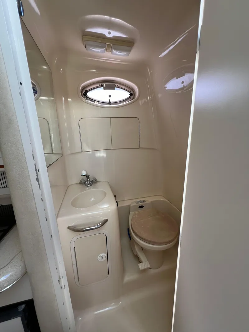 Slide: The Image of 2001 Sea Ray 270 Sundancer bathroom with sink, toilet, and porthole window. - 16