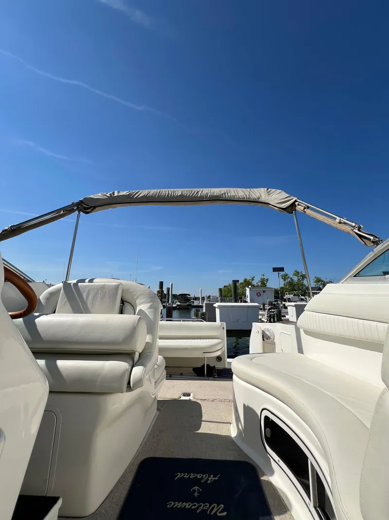 Slide: The Image of 2001 Sea Ray 270 Sundancer boat interior with white leather seats and blue sky background. - 24