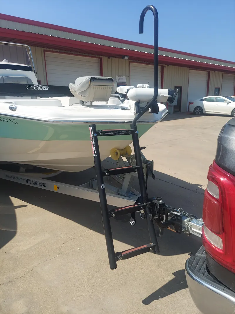 Slide: The Image of 2021 NauticStar 211 Hybrid boat hitched to a truck in a parking lot. - 21