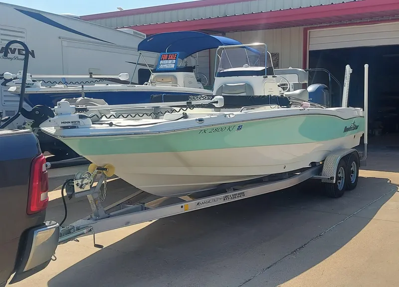 Slide: The Image of 2021 NauticStar 211 Hybrid boat on a trailer in a marina. - 3