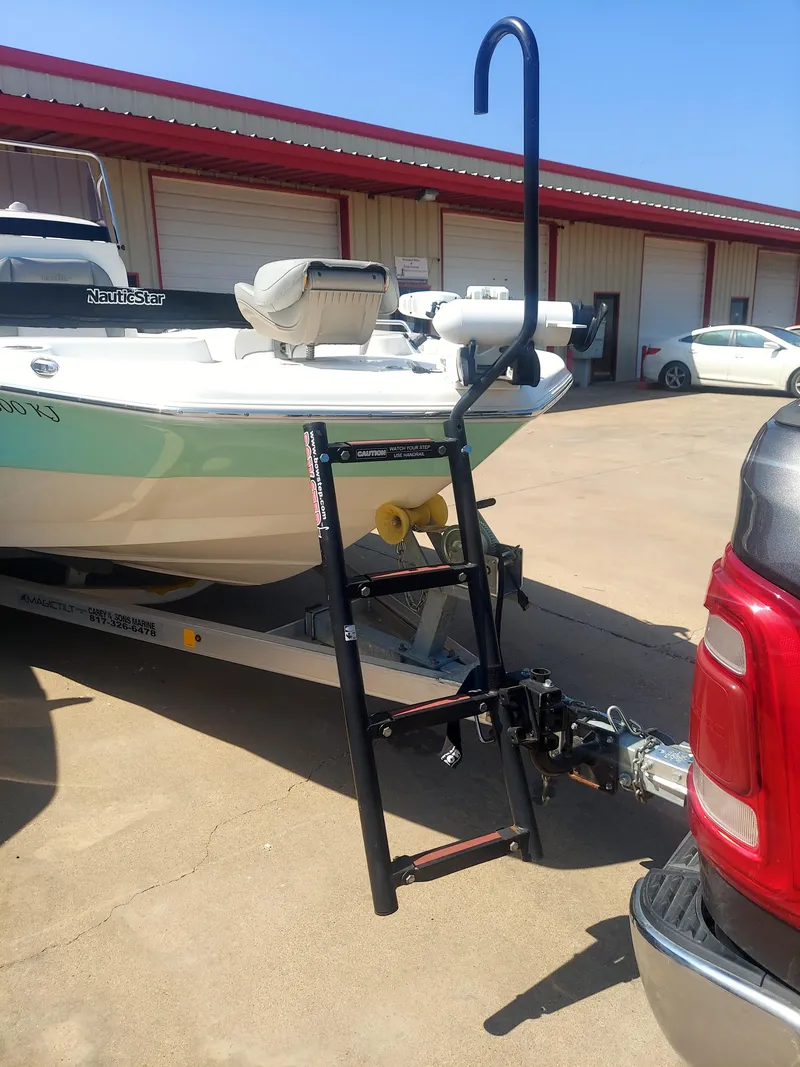 Slide: The Image of 2021 NauticStar 211 Hybrid boat hitched to a truck in a parking lot. - 6