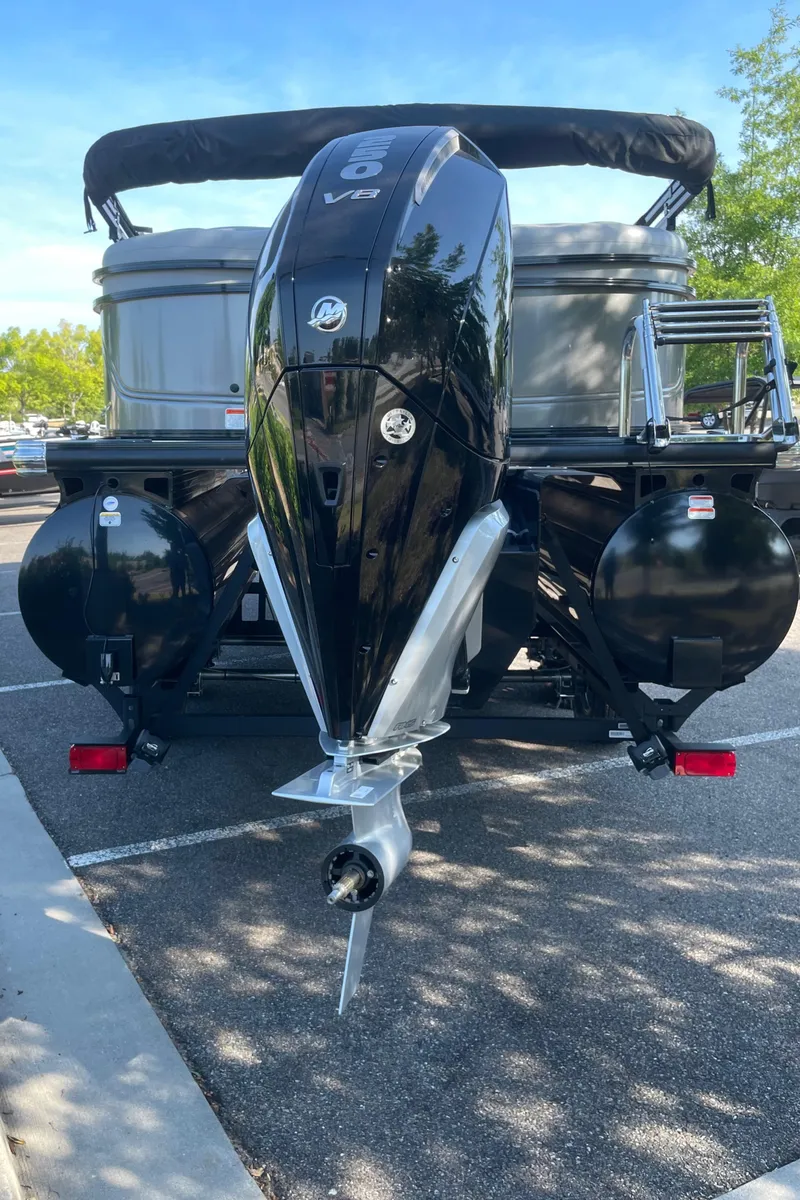 Slide: The Image of 2024 Regency 230 DL3 pontoon boat with powerful outboard motor in a parking lot. - 5