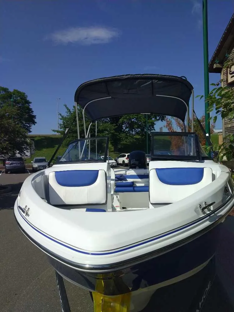 Slide: The Image of 2024 Tahoe 200 S boat with blue and white seating, parked outdoors. - 2