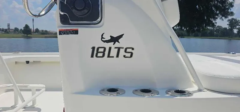 Slide: The Image of 2024 Mako 18 LTS boat console with rod holders by the water. - 2