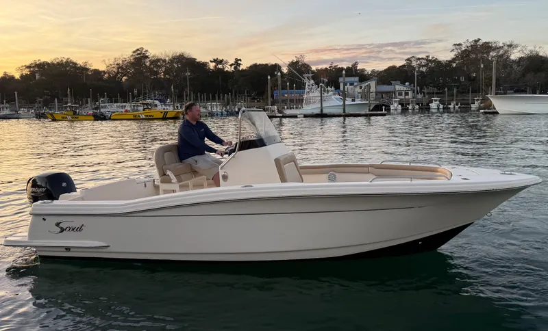 Slide: The Image of 2021 Scout 215 XSF boat cruising on calm water at sunset. - 2
