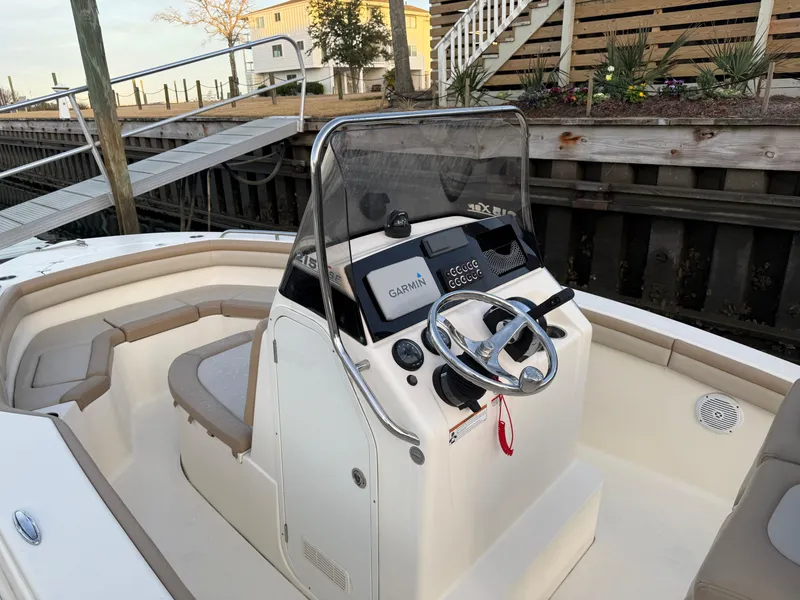 Slide: The Image of 2021 Scout 215 XSF boat console with Garmin navigation, docked by wooden pier. - 21